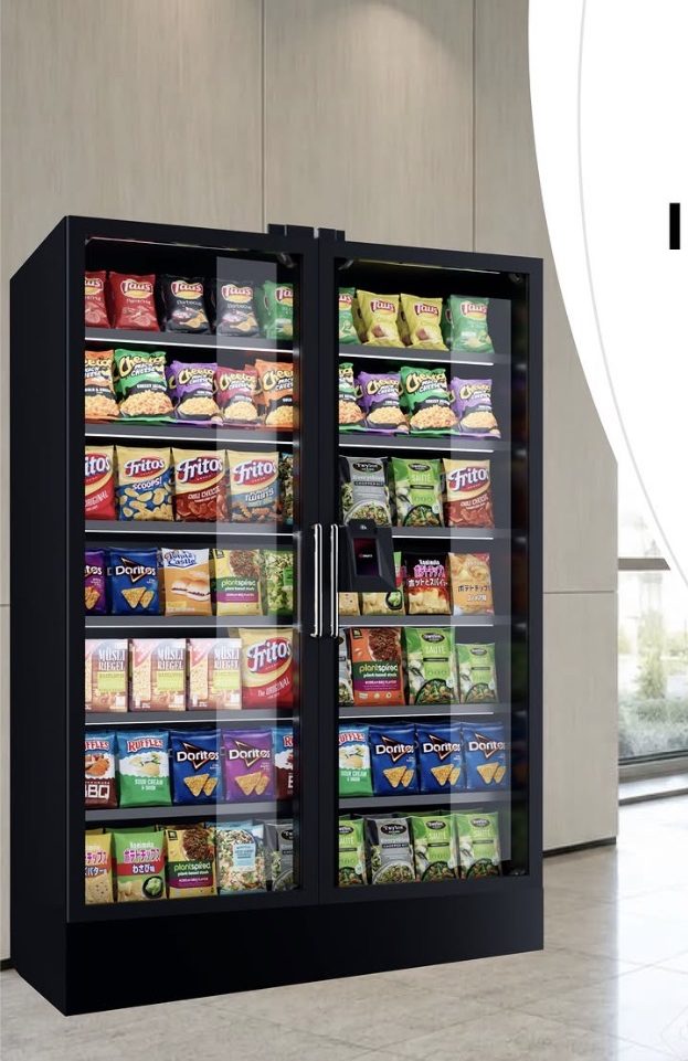 A locked glass ambient smart case stocked with snacks in a bright office lobby