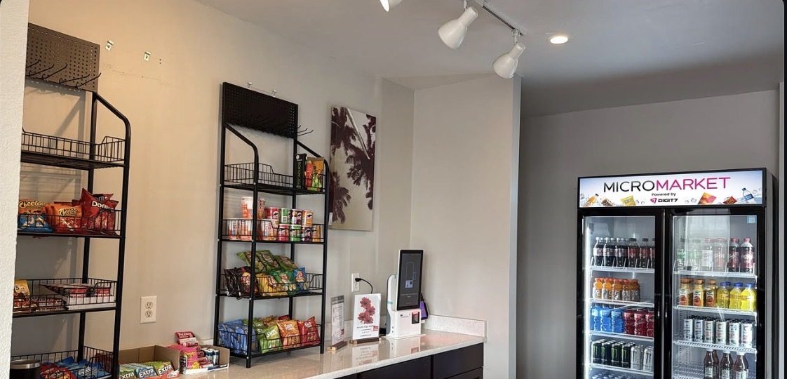 A live hotel micro market installation with snack racks, a checkout kiosk, and a smart cooler